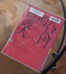 八尺門的辯護人 唐福睿著, a red cover with black brush-stroke characters, photographed on a wooden table.